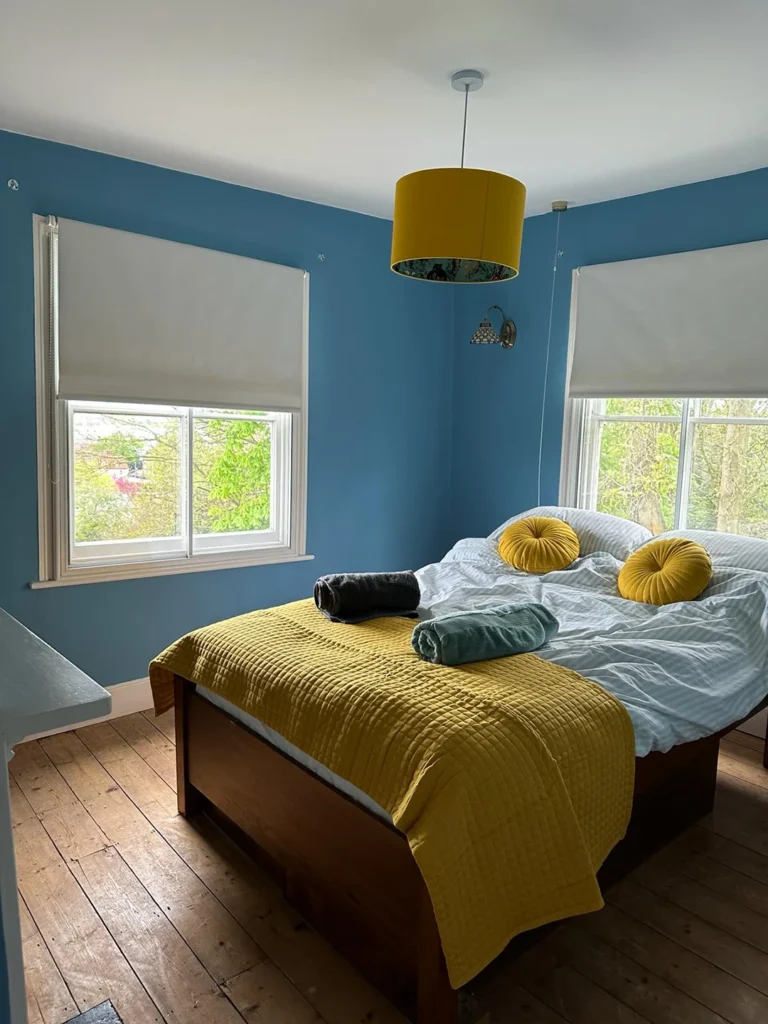 A bed with yellow pillows and a yellow lamp.
